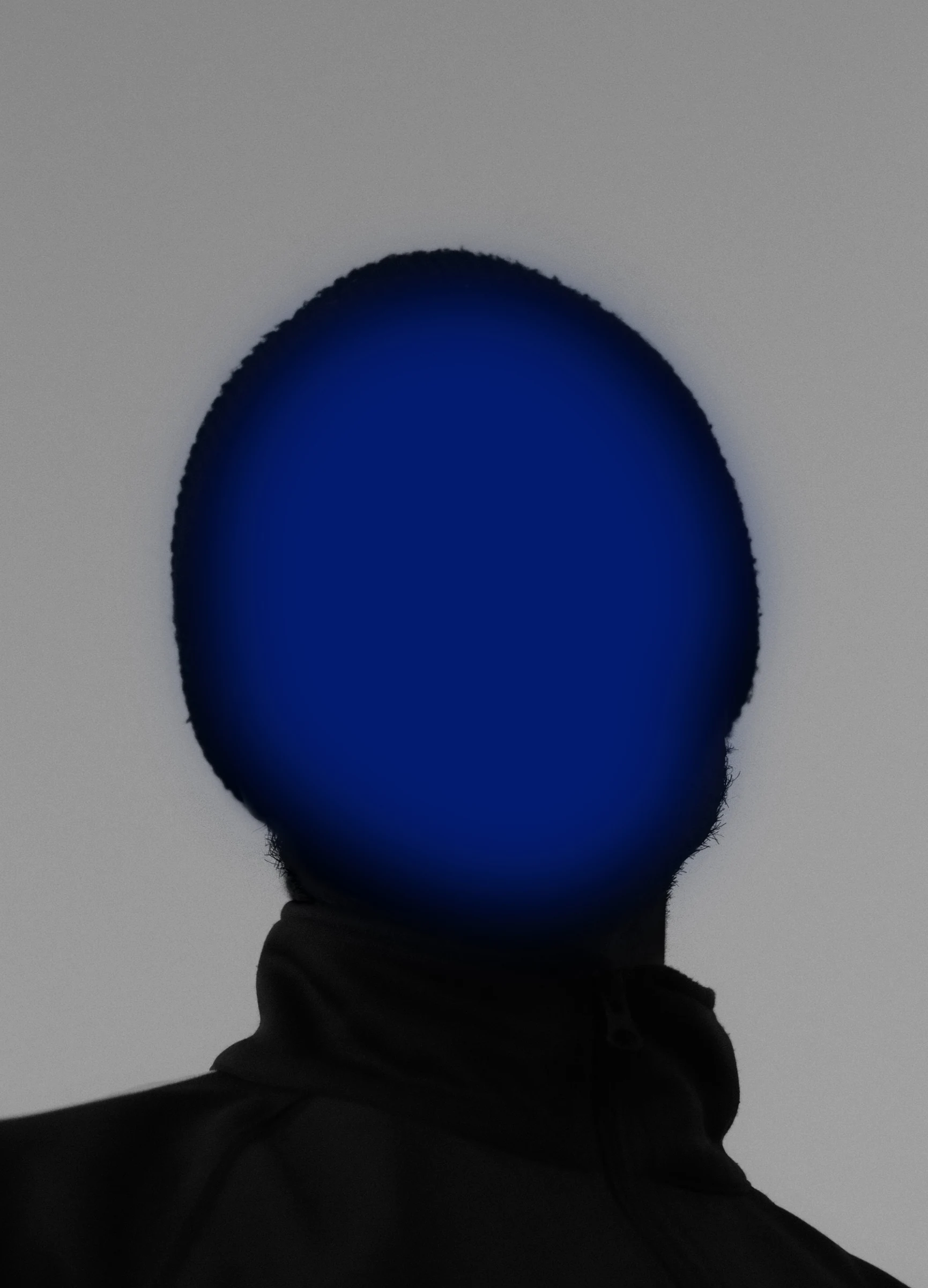 Close portrait silhouette with a vivid blue face-shaped light against a grey background