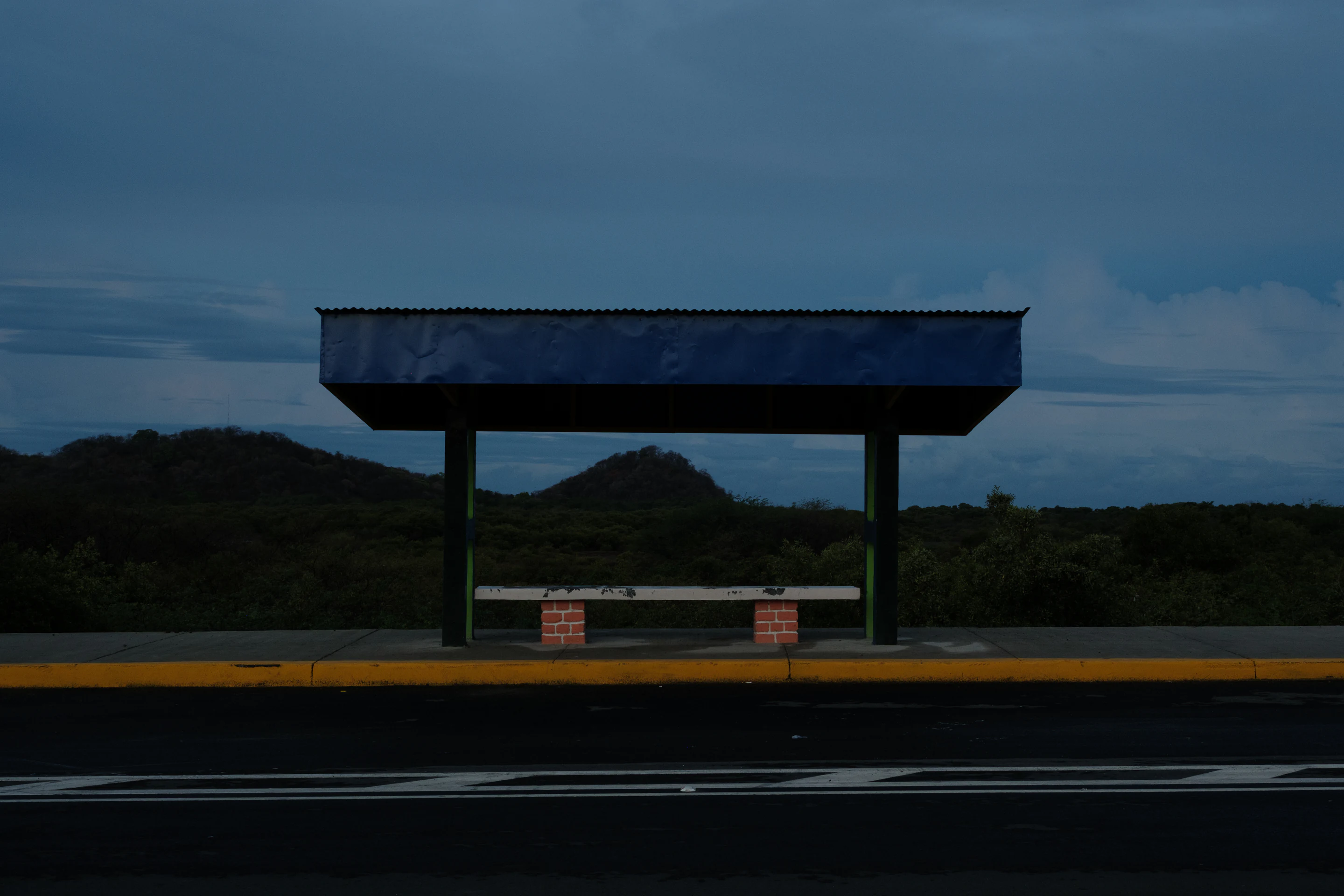 Quiet roadside shelter under a blue storm sky with dark hills in the background