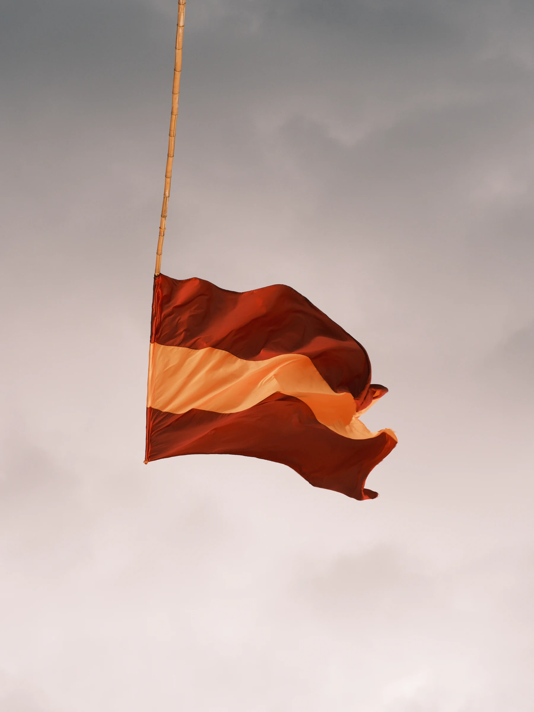 Red and white flag moving in the wind against a soft cloudy sky